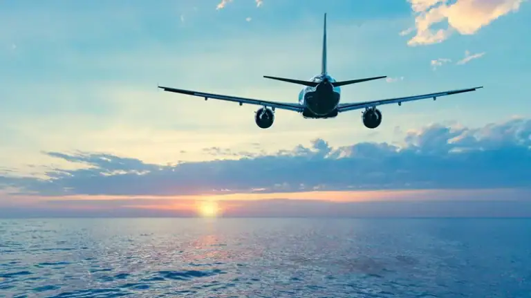 1. Commercial airplane flying over ocean at sunset, global travel.